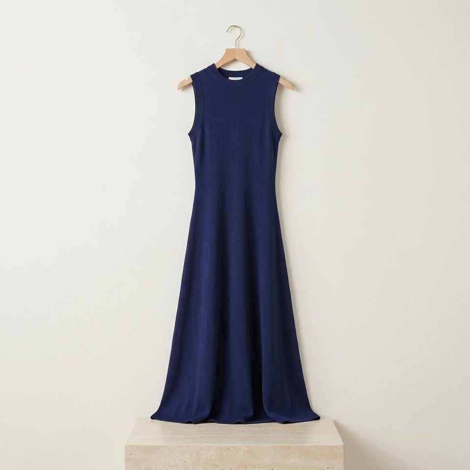 Vestido de punto marino sin mangas colgado ante una pared blanca
